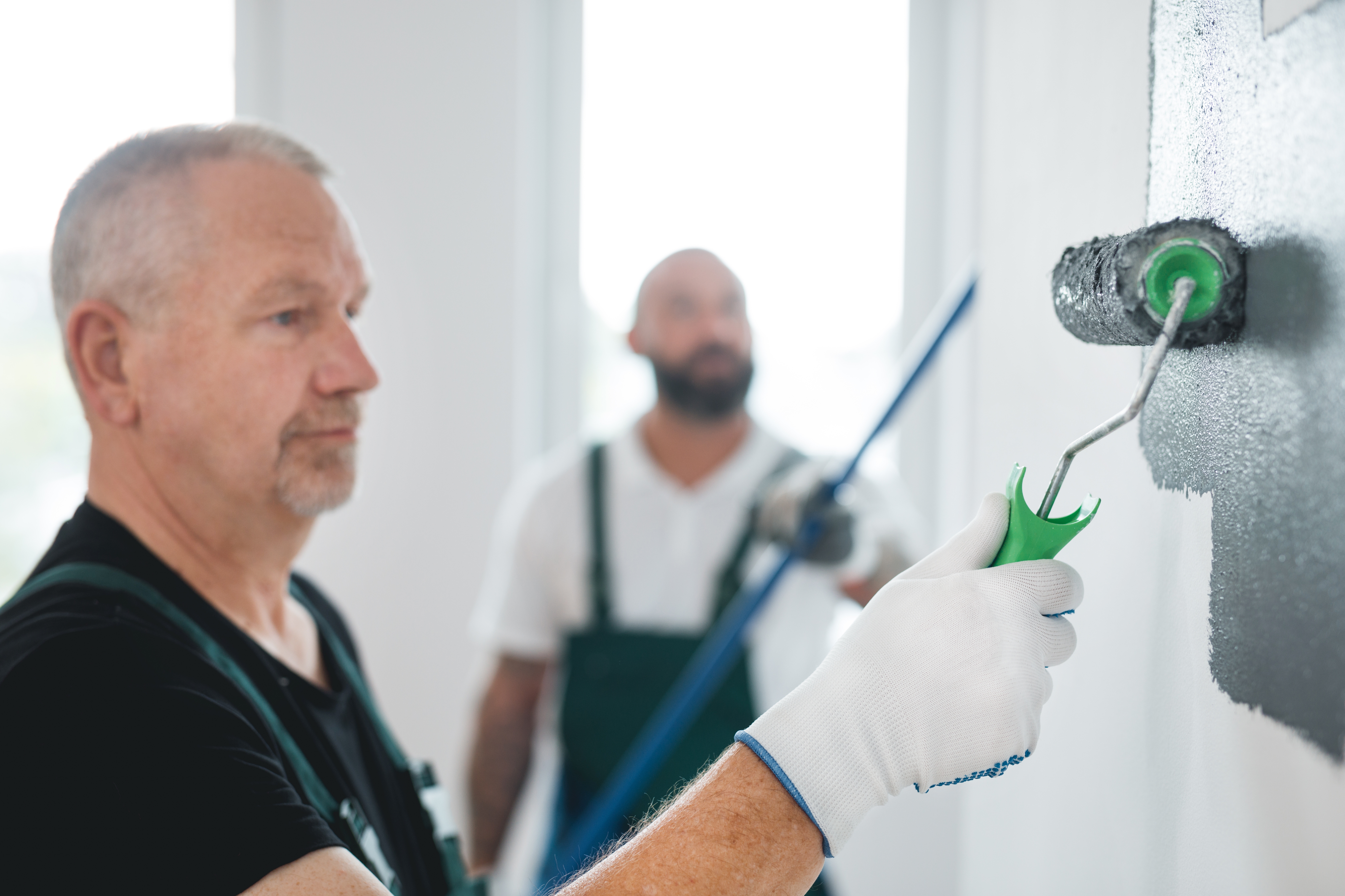 two men painting white walls gray